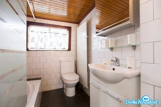 The bathroom offers a toilet, small bath and shower.