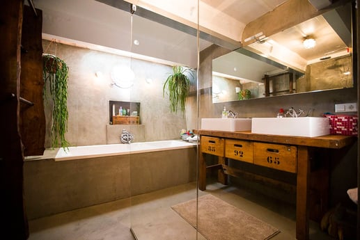 De industriële stijl badkamer met groot ligbad en wastafels.