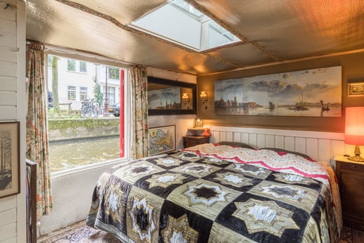 De slaapkamer met uitzicht op het water en het grote Nederlandse schilderij van de Haarlemerpoort in Amsterdam tijdens de Spaanse bezetting.