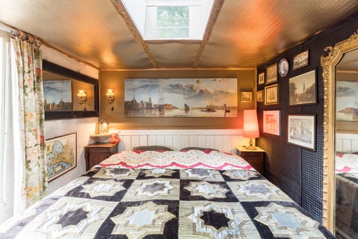 De slaapkamer met het kingsize bed, de schilderijen en de Louis XV-spiegel.