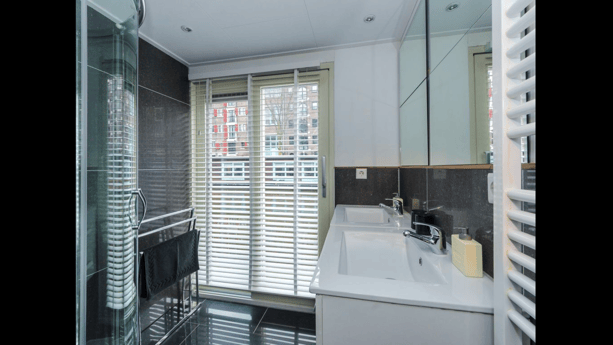 Badkamer met douchecabine en dubbele wastafel