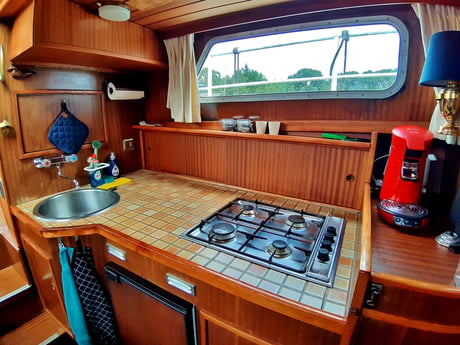 Cocina equipada con vitrocerámica de 4 fuegos, cafetera, hervidor eléctrico, nevera pequeña y vajilla.